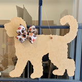 three spoiled dogs customizable golden doodle welcome door hanger with a fall football bow hanging on a front door