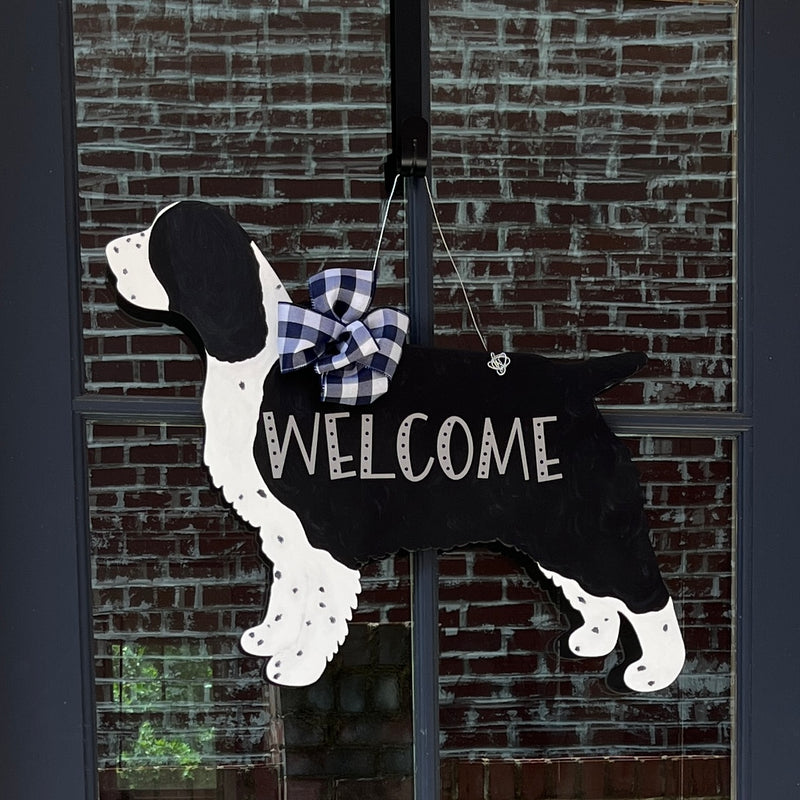 three spoiled dogs customizable springer spaniel welcome door hanger with a navy buffalo plaid bow hanging on a front door